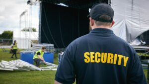 Rear View Of Security Team At Outdoor Stage For Music Festival Or Concert