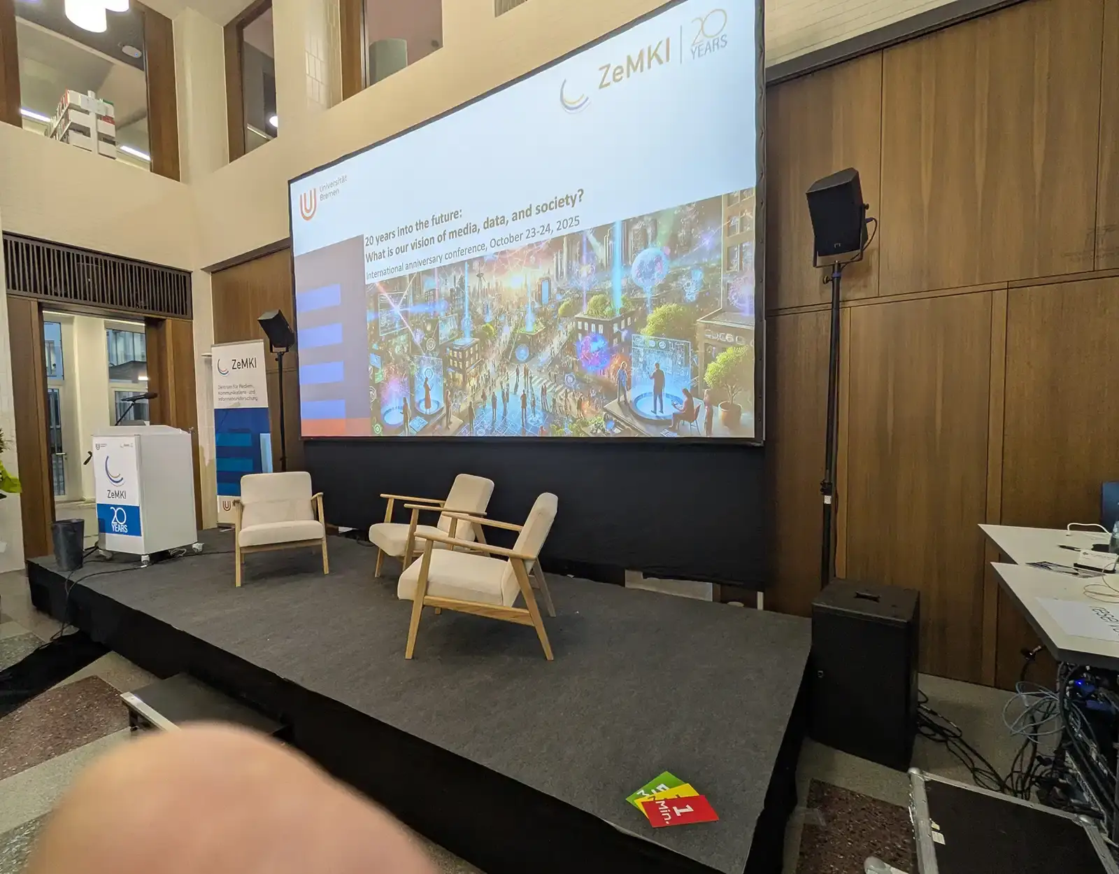 Professionelles Technik-Setup für ein Symposium in OWL mit Rednerpult, Sennheiser Mikrofon, großer Projektionsleinwand und diskretem Soundsystem vor Fachpublikum.