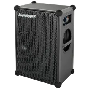 Mobiler Akku-Bluetooth-Lautsprecher SOUNDBOKS 4 in Schwarz mit robustem Pappelholzgehäuse, Eckschützern, seitlichen Tragegriffen und Waben-Frontgitter frei stehend vor neutralem Studiolook-Hintergrund.