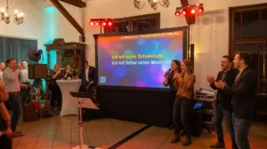 Stimmungsvolle Karaoke-Weihnachtsfeier in Bünde mit professioneller Karaokeanlage und Funkmikrofonen von PvD - Events & Technik: Gäste singen vor einer mobilen Beamer-Leinwand mit Textanzeige in einem festlichen Saal.
